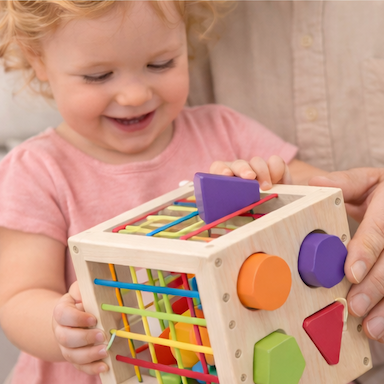 Toddler learning shapes with wooden Montessori cube