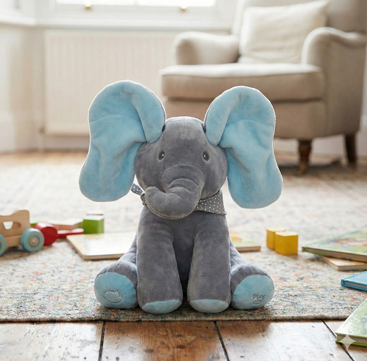 Plush elephant toy with blue ears on a wooden floor in a room with toys and furniture.